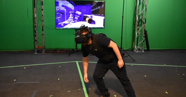 a man standing in front of a screen with a virtual reality headset on
